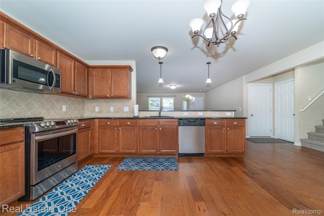 750 Dewars St, Howell, MI 48843 - kitchen featuring stainless steel appliances, dark wood-style floors, a peninsula, tasteful backsplash, and brown cabinetry