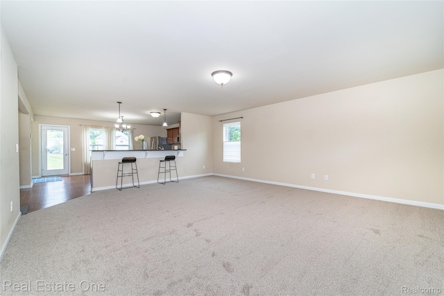 750 Dewars St, Howell, MI 48843 - unfurnished living room with light colored carpet and a chandelier