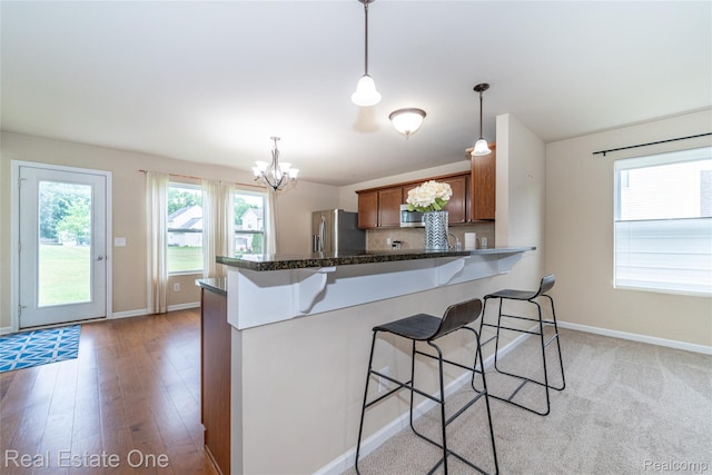 750 Dewars St, Howell, MI 48843 - kitchen with appliances with stainless steel finishes, brown cabinets, a breakfast bar area, and a chandelier