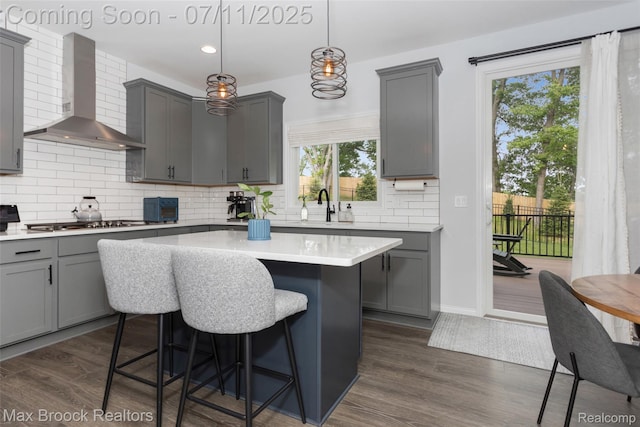 460 Lake Manitou Trl, Oxford, MI 48371 - kitchen featuring wall chimney exhaust hood, gray cabinets, stainless steel gas stovetop, a breakfast bar, and tasteful backsplash