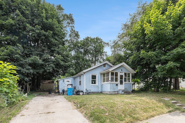 1638 Cherry St, Niles, MI 49120 - view of front facade featuring a sunroom, a chimney, a front yard, and driveway