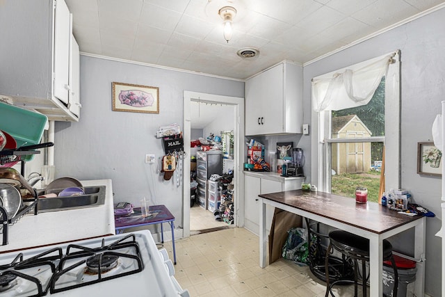 1638 Cherry St, Niles, MI 49120 - kitchen with crown molding, white cabinetry, light flooring, and white range with gas stovetop
