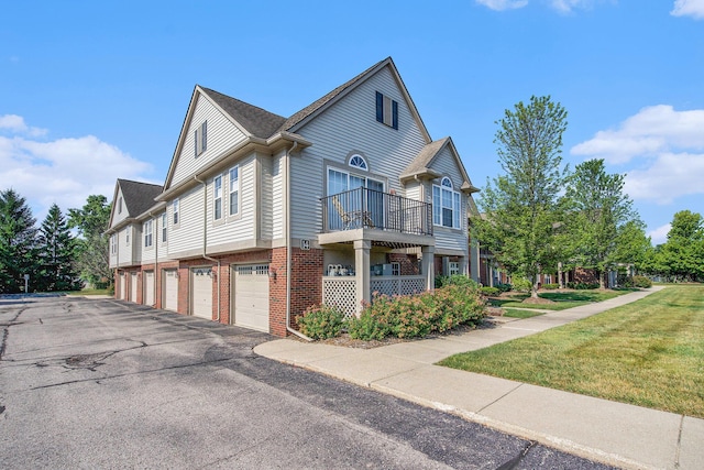 3132 Primrose Ln, Ypsilanti, MI 48197 - view of side of home with driveway, a lawn, brick siding, a balcony, and an attached garage