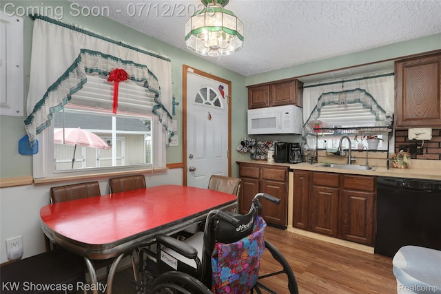 4313 S Dearborn St, Melvindale, MI 48122 - kitchen with white microwave, black dishwasher, light wood-type flooring, a textured ceiling, and light countertops