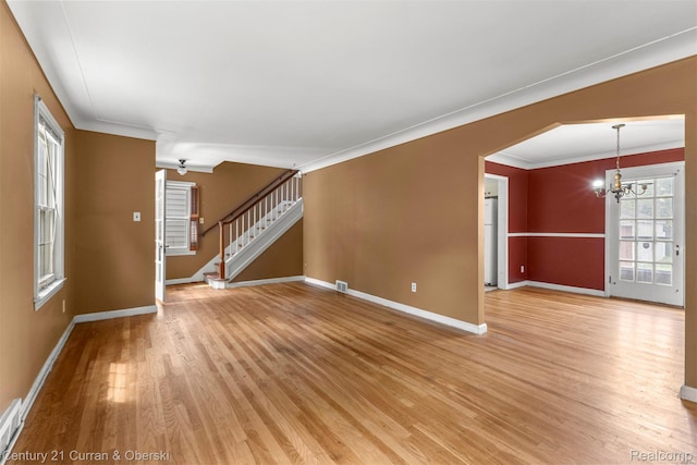 711 N Highland St, Dearborn, MI 48128 - unfurnished living room with a chandelier, light wood finished floors, stairway, ornamental molding, and arched walkways