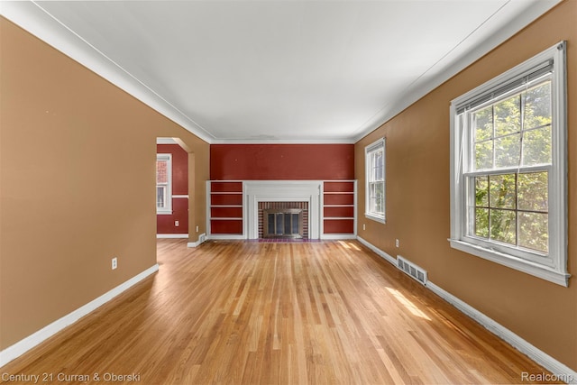 711 N Highland St, Dearborn, MI 48128 - unfurnished living room with light wood finished floors, arched walkways, a brick fireplace, and crown molding