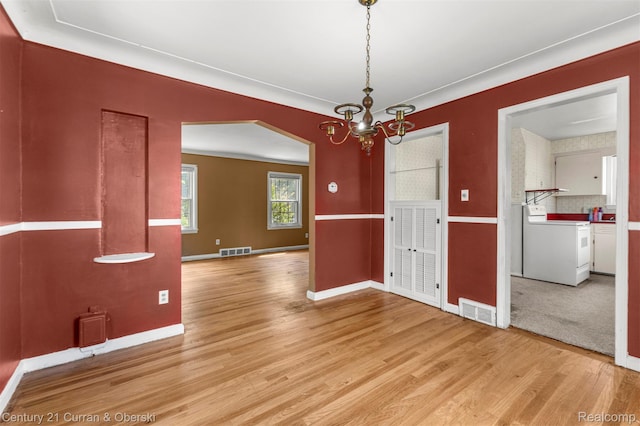 711 N Highland St, Dearborn, MI 48128 - empty room featuring light wood-type flooring, washing machine and clothes dryer, a chandelier, and arched walkways
