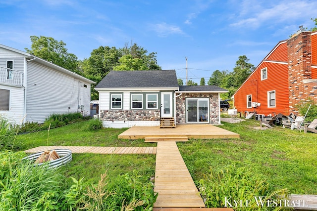 12230 Mac Dr NE, Belding, MI 48809 - rear view of house with stone siding, a yard, a shingled roof, and an outdoor structure