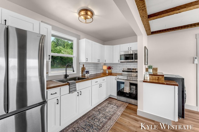 12230 Mac Dr NE, Belding, MI 48809 - kitchen with stainless steel appliances, decorative backsplash, white cabinets, butcher block countertops, and light wood finished floors