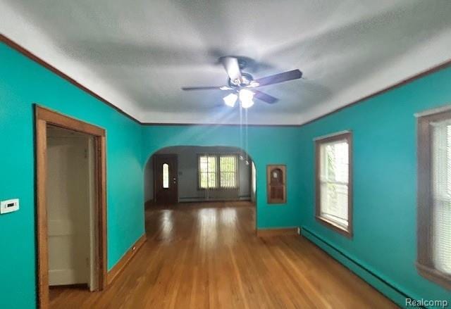 2170 Avondale St, Sylvan Lake, MI 48320 - empty room with arched walkways, a baseboard radiator, a ceiling fan, and wood finished floors