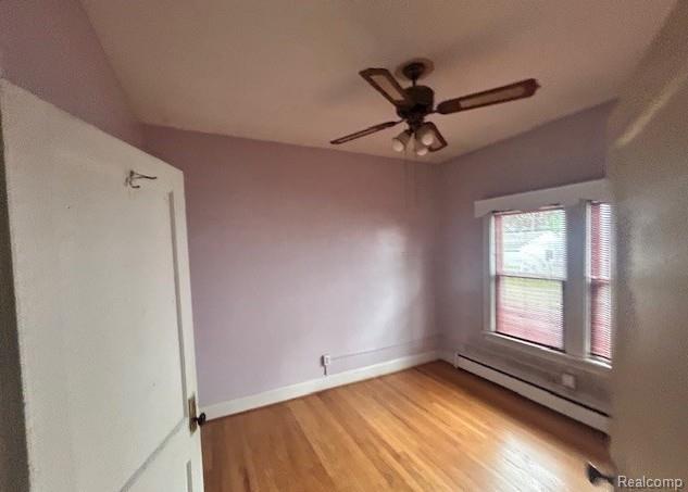 2170 Avondale St, Sylvan Lake, MI 48320 - spare room featuring baseboard heating, a ceiling fan, and light wood-style floors