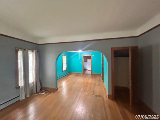 2170 Avondale St, Sylvan Lake, MI 48320 - unfurnished room featuring a baseboard radiator, light wood-type flooring, arched walkways, and baseboard heating