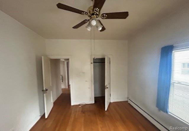 2170 Avondale St, Sylvan Lake, MI 48320 - unfurnished bedroom featuring a baseboard heating unit, wood finished floors, and a ceiling fan