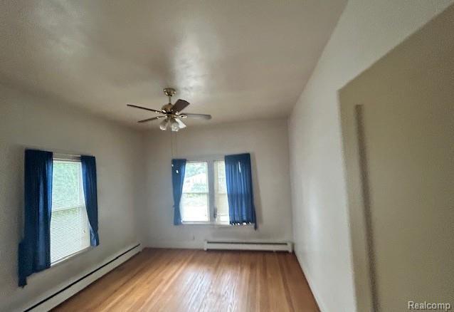 2170 Avondale St, Sylvan Lake, MI 48320 - unfurnished room with baseboard heating, a baseboard radiator, plenty of natural light, and wood finished floors