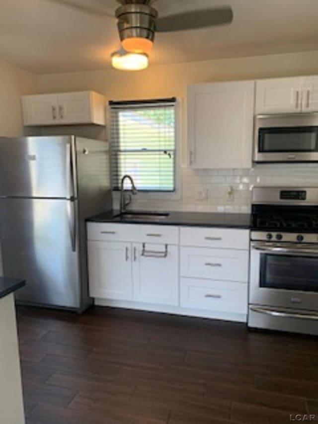 609 Orchard Ln, Tecumseh, MI 49286 - kitchen featuring appliances with stainless steel finishes, dark countertops, white cabinets, dark wood-style flooring, and tasteful backsplash