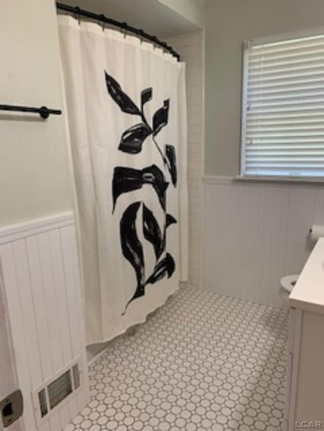 609 Orchard Ln, Tecumseh, MI 49286 - full bath featuring a wainscoted wall, vanity, and a shower with curtain
