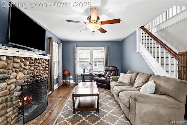 342 King St, Highland, MI 48357 - living room featuring wood finished floors, a ceiling fan, a stone fireplace, and stairway