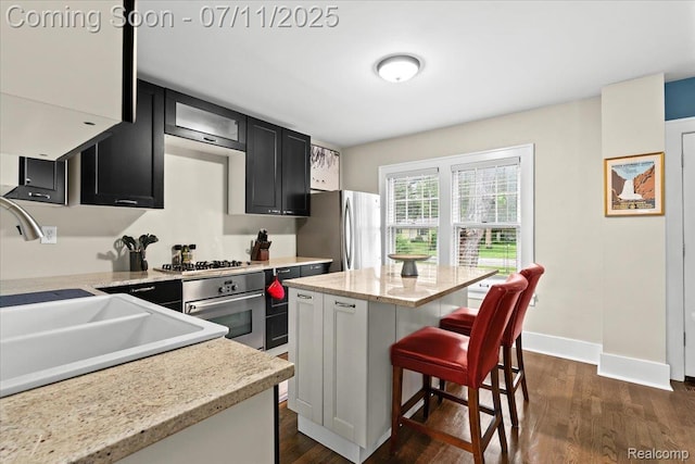 342 King St, Highland, MI 48357 - kitchen with stainless steel appliances, dark cabinetry, dark wood finished floors, a breakfast bar, and a kitchen island