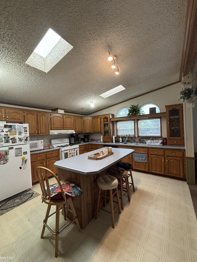 2500 Mann Rd, Clarkston, MI 48356 - kitchen with white appliances, a skylight, brown cabinets, a textured ceiling, and a center island