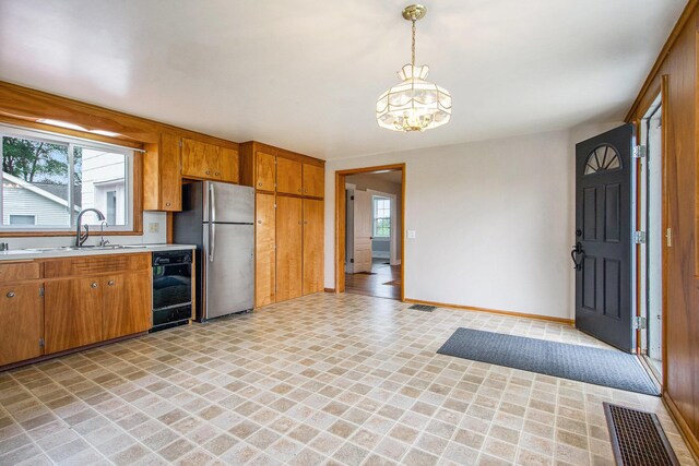 9148 Austin Rd, Saline, MI 48176 - kitchen featuring dishwasher, freestanding refrigerator, light countertops, brown cabinetry, and a chandelier