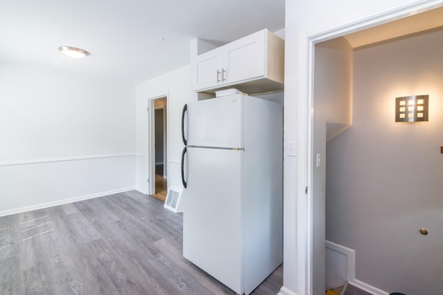 11015 Fairfield St, Livonia, MI 48150 - kitchen with freestanding refrigerator, white cabinetry, and wood finished floors