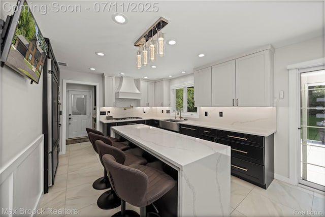 5534 Apple Ridge Trl, West Bloomfield, MI 48322 - kitchen with custom range hood, dark cabinetry, a center island, pendant lighting, and light stone counters