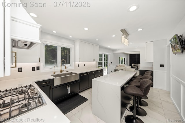 5534 Apple Ridge Trl, West Bloomfield, MI 48322 - kitchen featuring stainless steel gas stovetop, dark cabinetry, open floor plan, a kitchen breakfast bar, and custom exhaust hood