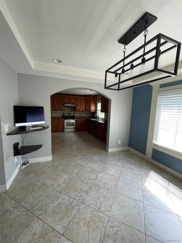 23364 Clark Rd, Belleville, MI 48111 - kitchen with stainless steel electric range, arched walkways, backsplash, open floor plan, and dark countertops
