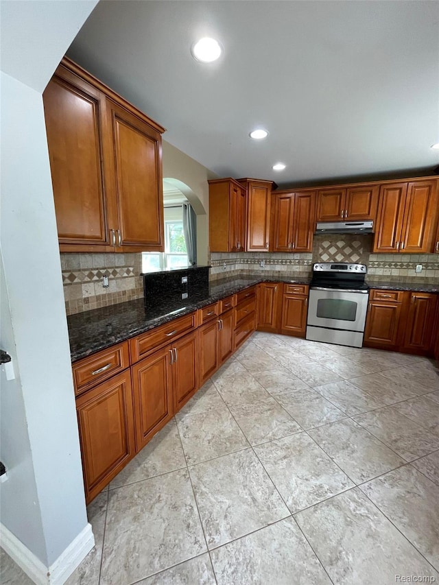23364 Clark Rd, Belleville, MI 48111 - kitchen with electric range, under cabinet range hood, arched walkways, backsplash, and brown cabinets