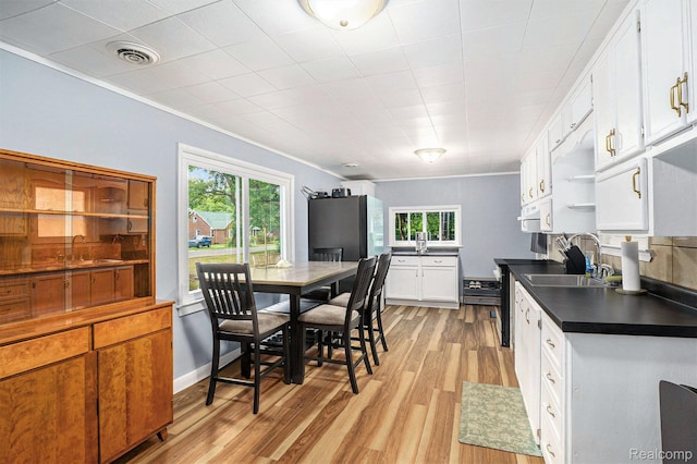 124 N Line St, Chesaning, MI 48616 - kitchen with dark countertops, white cabinetry, plenty of natural light, light wood finished floors, and crown molding