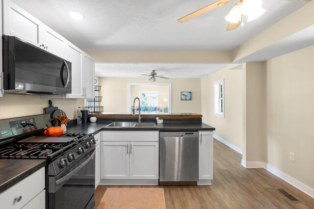 5743 107th Ave, Pullman, MI 49450 - kitchen with black appliances, a ceiling fan, a peninsula, dark countertops, and light wood-style flooring