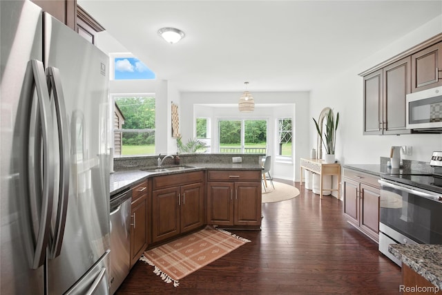 27245 Ritter Blvd, Flat Rock, MI 48134 - kitchen featuring stainless steel appliances, dark wood-style floors, dark stone counters, hanging light fixtures, and a peninsula