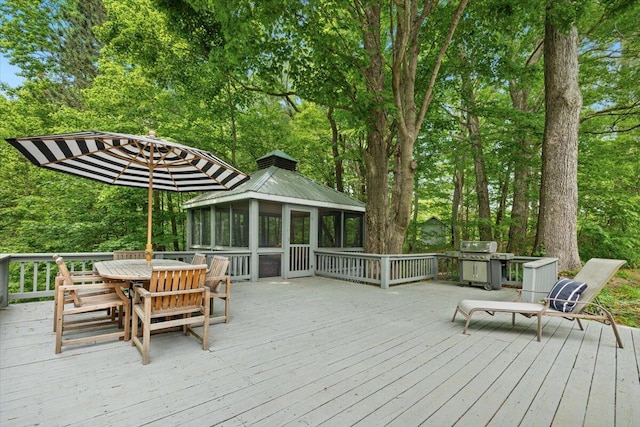 5515 Kaiser Rd, Sawyer, MI 49125 - deck with outdoor dining area, a sunroom, area for grilling, and view of wooded area