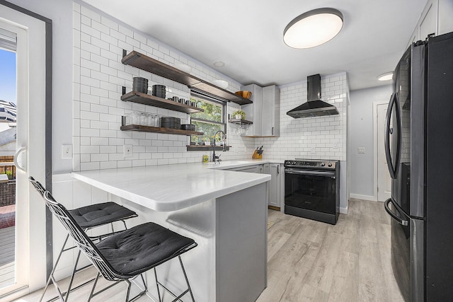 1440 Chevelle, Jenison, MI 49428 - kitchen with freestanding refrigerator, stainless steel range with electric stovetop, wall chimney exhaust hood, backsplash, and a peninsula