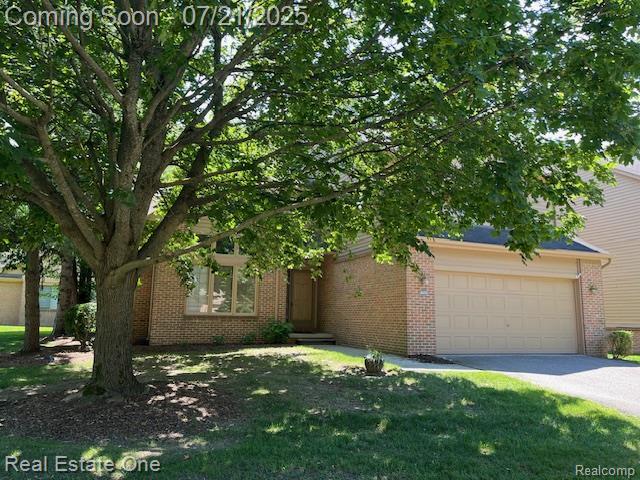 6630 Heron Pt, West Bloomfield, MI 48323 - obstructed view of property with an attached garage, brick siding, driveway, and a front yard