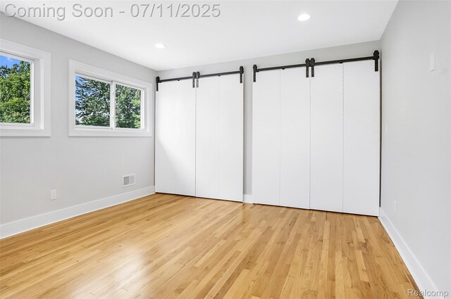 22222 Evergreen St, Macomb, MI 48082 - unfurnished bedroom featuring wood finished floors, a barn door, and recessed lighting