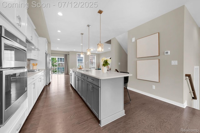 2825 Ridington Rd, Ann Arbor, MI 48105 - kitchen featuring appliances with stainless steel finishes, gray cabinets, dark wood-style floors, a breakfast bar, and light countertops