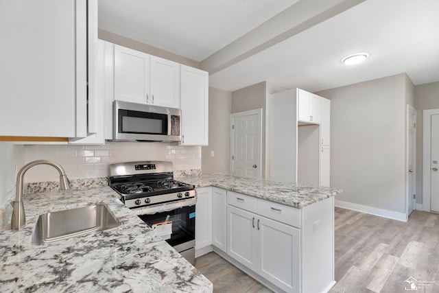2651 Lakewood St, Detroit, MI 48215 - kitchen with appliances with stainless steel finishes, a peninsula, light stone counters, white cabinetry, and tasteful backsplash