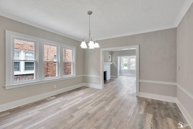 2651 Lakewood St, Detroit, MI 48215 - unfurnished dining area featuring a chandelier, light wood-type flooring, a textured ceiling, a brick fireplace, and crown molding