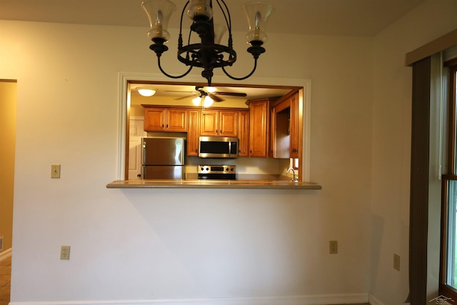11731 Birch Run Rd, Birch Run, MI 48415 - kitchen featuring stainless steel appliances, a chandelier, brown cabinetry, ceiling fan, and a peninsula