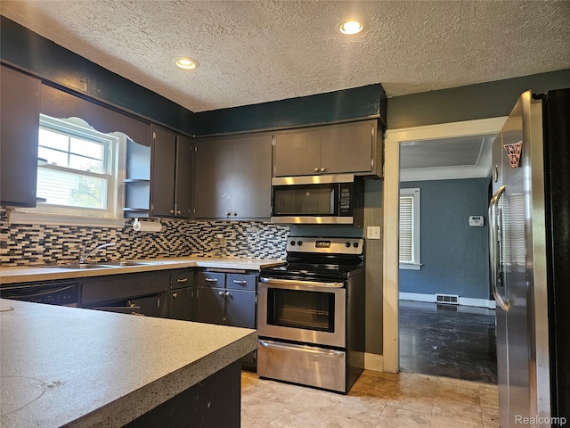 607 Roome Ct, Flint, MI 48503 - kitchen featuring appliances with stainless steel finishes, backsplash, a textured ceiling, light countertops, and recessed lighting