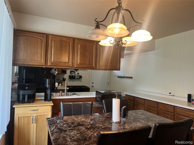 33158 Shawnee St, Westland, MI 48185 - kitchen with stainless steel microwave, brown cabinetry, hanging light fixtures, and dark stone countertops
