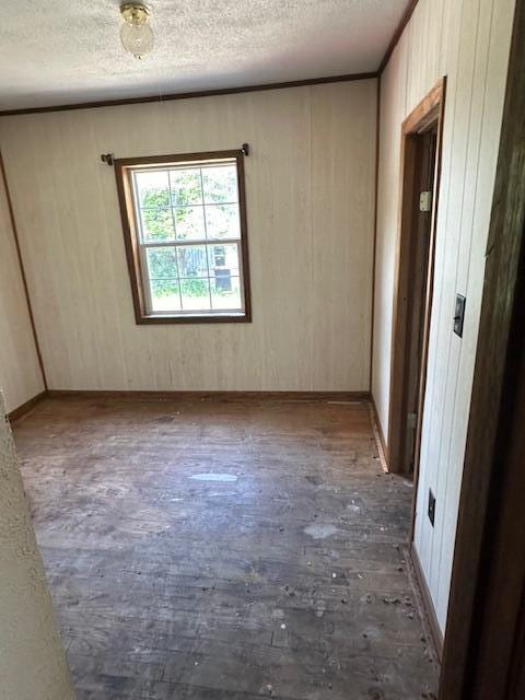 1675 E 8th St, White Cloud, MI 49349 - unfurnished room featuring a textured ceiling, wood finished floors, and wood walls
