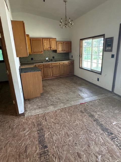1675 E 8th St, White Cloud, MI 49349 - kitchen featuring a chandelier, high vaulted ceiling, brown cabinets, decorative light fixtures, and backsplash
