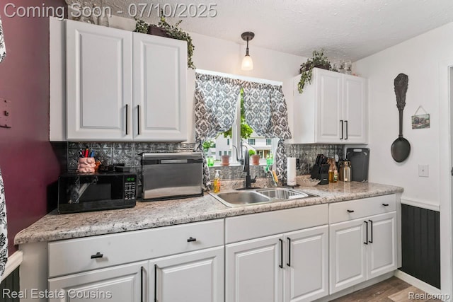 135 Bevins St, Holly, MI 48442 - kitchen with backsplash, white cabinetry, light countertops, a textured ceiling, and black microwave
