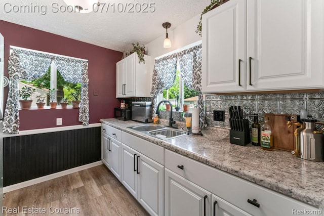 135 Bevins St, Holly, MI 48442 - kitchen with a textured ceiling, white cabinets, black microwave, light wood-type flooring, and decorative backsplash