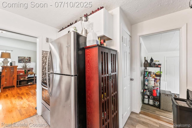 135 Bevins St, Holly, MI 48442 - kitchen featuring freestanding refrigerator, light wood finished floors, white cabinets, and a textured ceiling