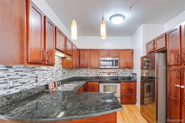 41666 Tera Ln, Novi, MI 48375 - kitchen with stainless steel appliances, light wood-style flooring, hanging light fixtures, a peninsula, and tasteful backsplash