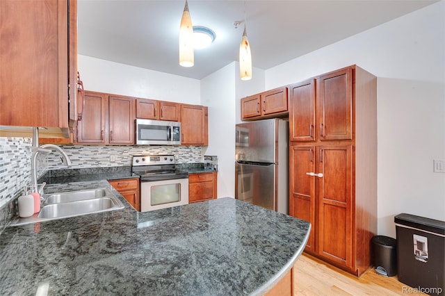 41666 Tera Ln, Novi, MI 48375 - kitchen featuring appliances with stainless steel finishes, decorative backsplash, a peninsula, light wood-style floors, and pendant lighting