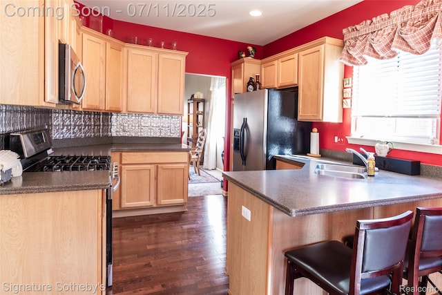 49866 Sleeping River Dr, Macomb, MI 48042 - kitchen featuring stainless steel appliances, a peninsula, dark countertops, dark wood-style floors, and a kitchen breakfast bar